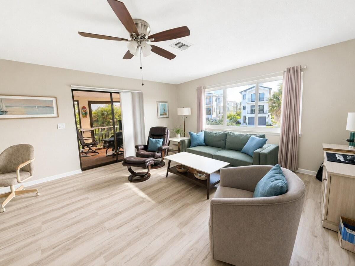 Large sun-drenched living area with 65” TV and private second floor lanai through sliding glass doors.